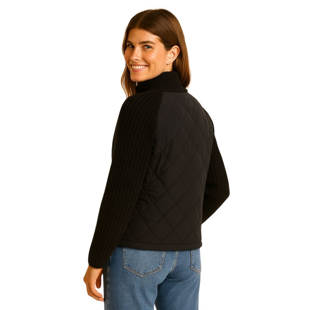 Model smiling in the black Kouvr Mika jacket, showing the side profile and texture of the knit sleeves.
