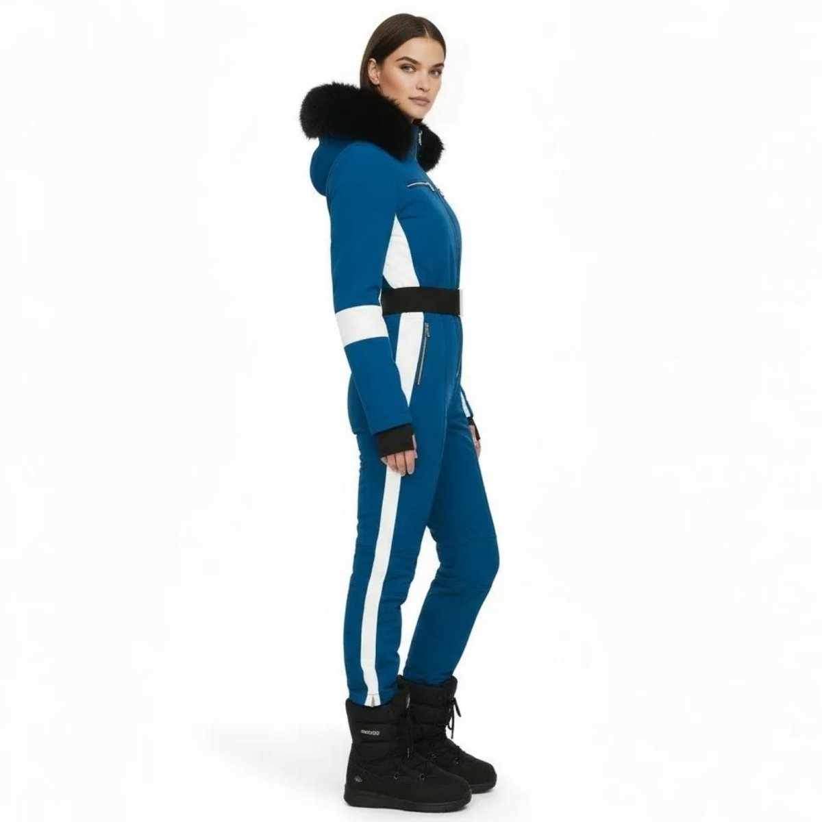Side profile of a woman in a slim fit blue belted ski suit with white stripe detail and black fur hood.
