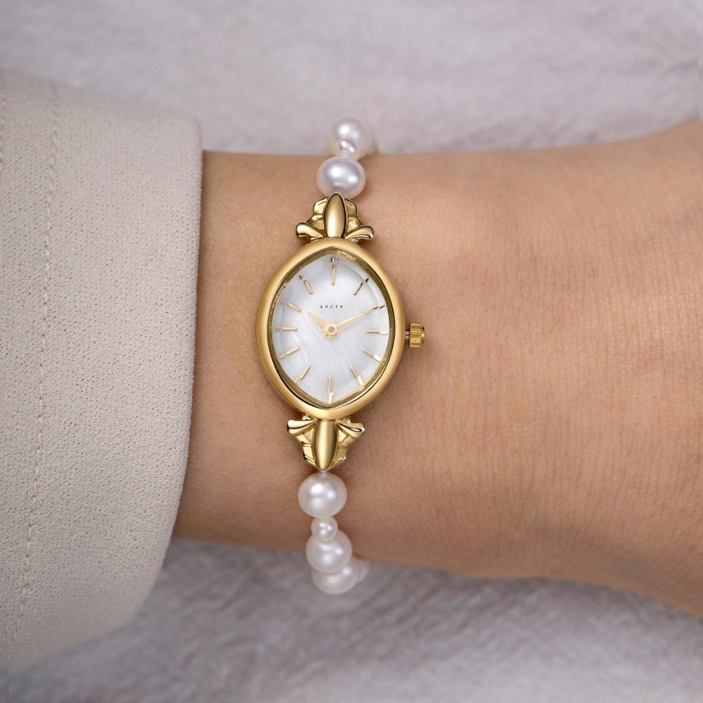 Gold Kouvr watch with pearl strap on a wrist against a neutral background