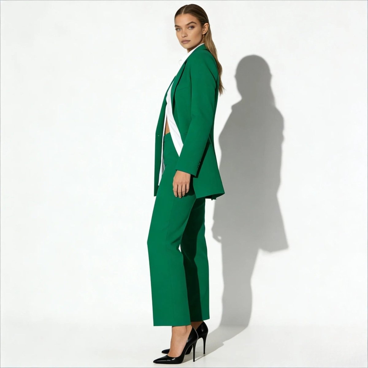 Side profile of a model in the Kouvr kate green pant suit, showing the drape of the oversized blazer and the fit of the wide-leg trousers.
