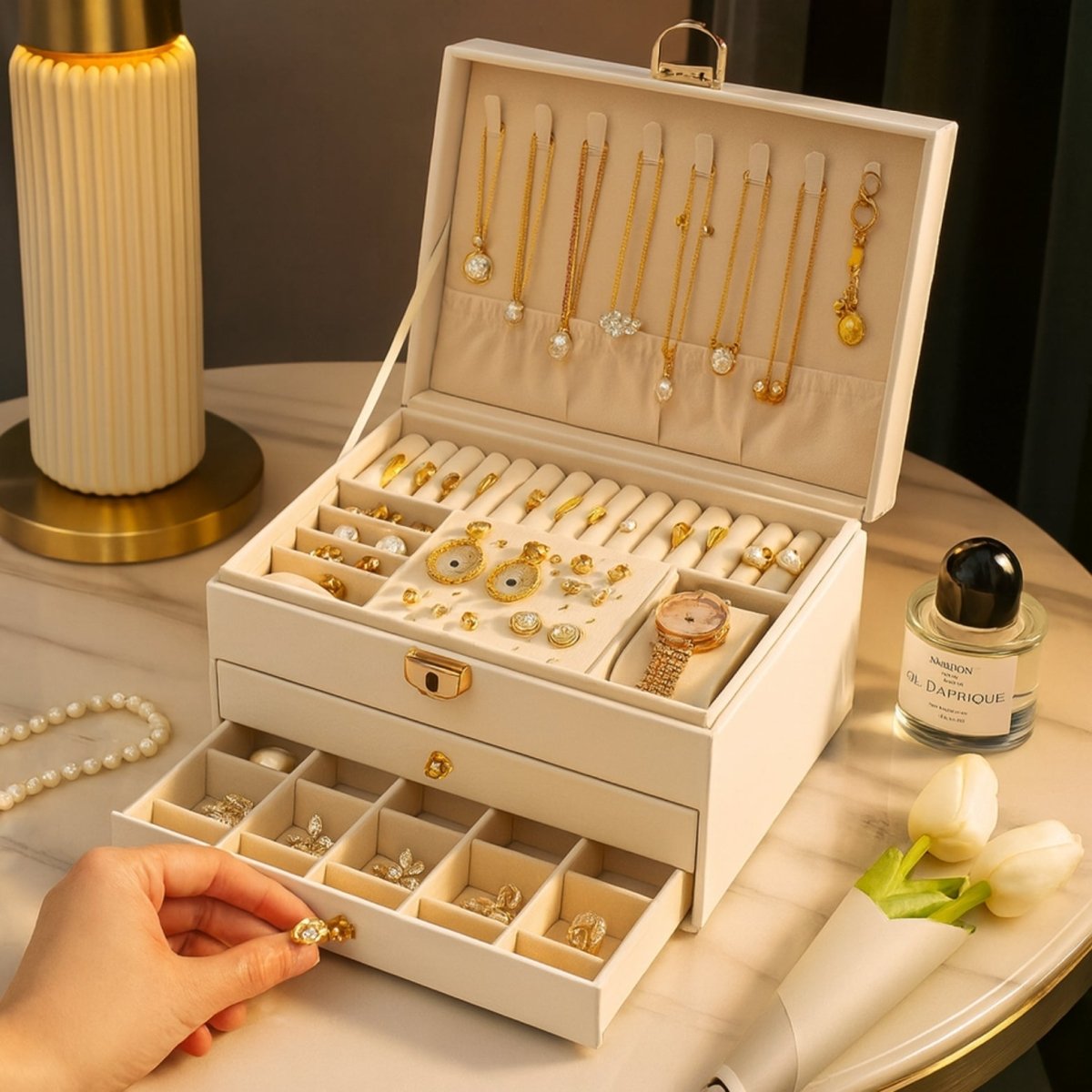 Woman's hand opening the bottom drawer of a white leather jewelry box organizer to place a ring inside.